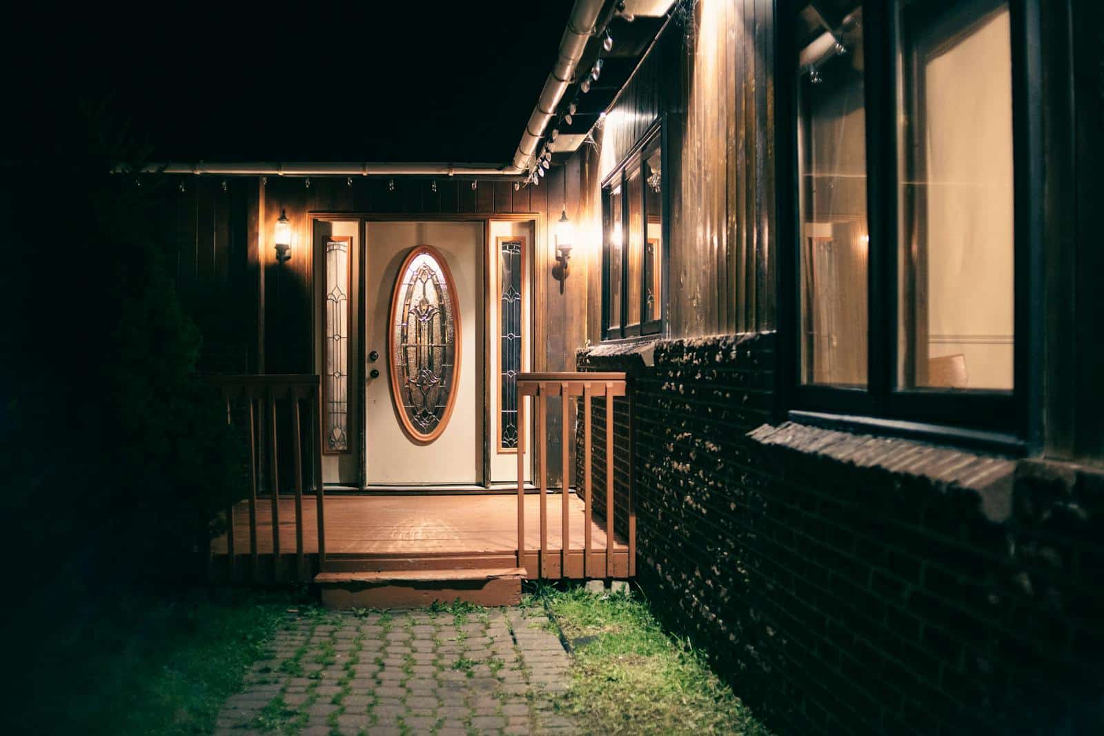 A warmly lit house entrance with decorative glass doors and glowing lantern lights at night.